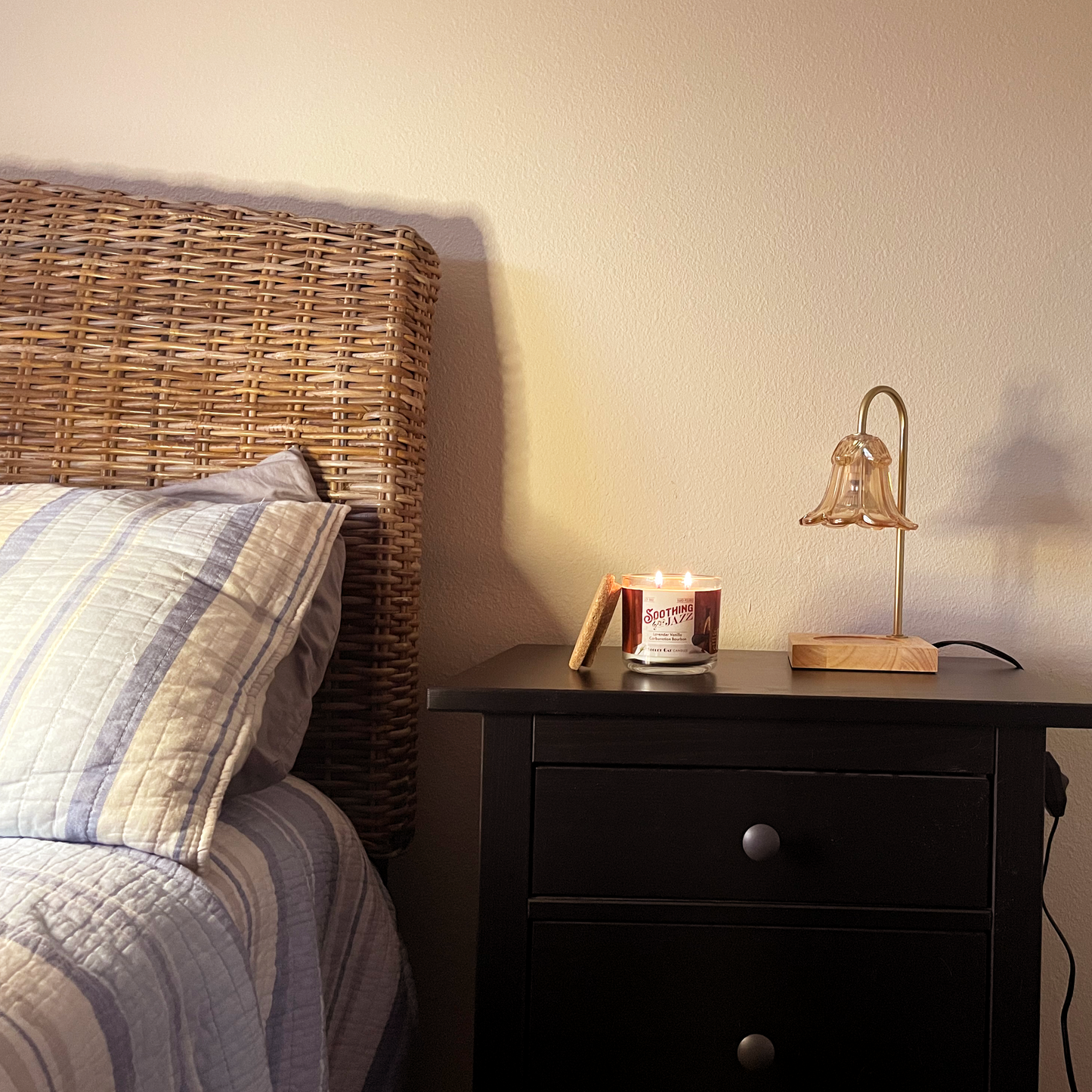 Bed scene with a lit candle on a nightstand next to a lamp with a bed on the left