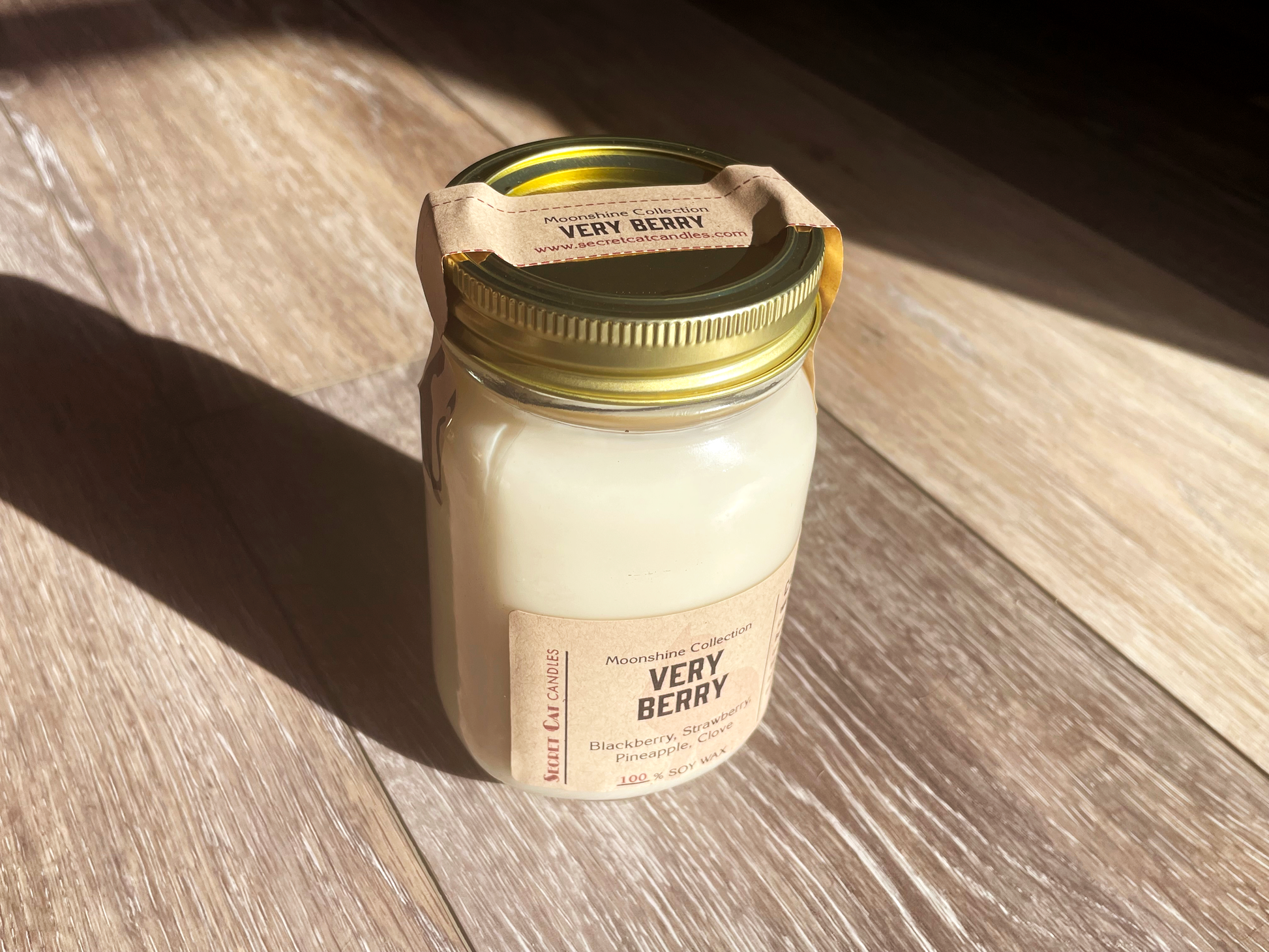 Side view of a candle in a mason jar with a wood grain background